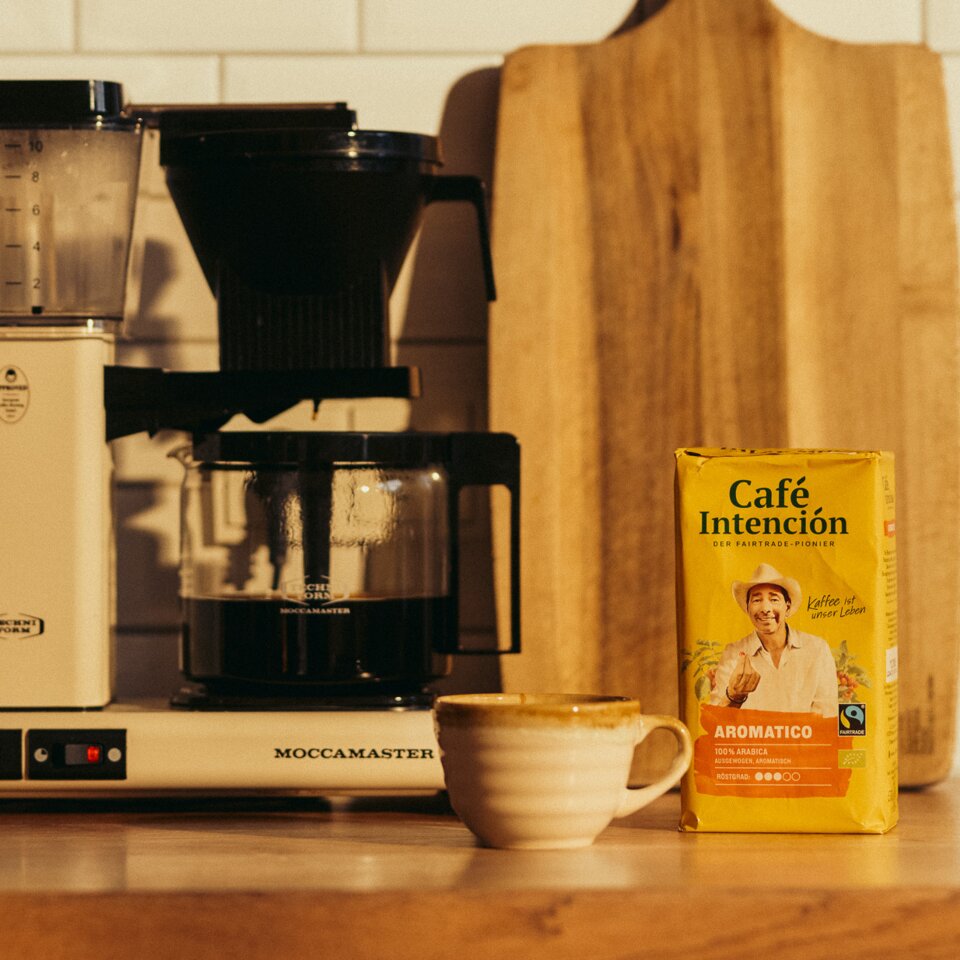 Ekspres do kawy Moccamaster obok opakowania Café Intención i filiżanki, w jasnej kuchni.